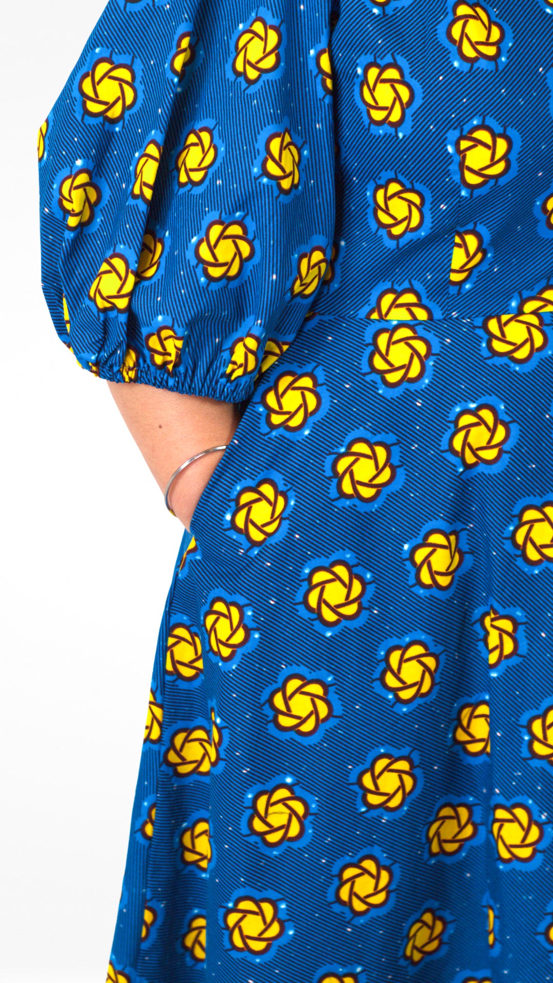 Close-up details of the fitted waistline and puff sleeves of the blue dress, accentuating its tailored design and the yellow elements.