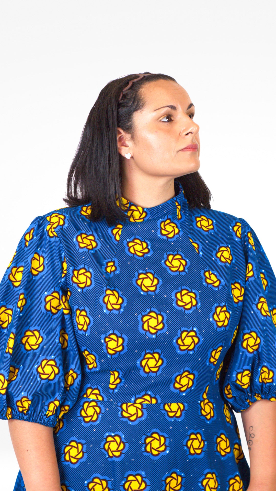 A close up of the top part of the blue puff sleeve dress, highlighting the vibrant yellow elements of the print.