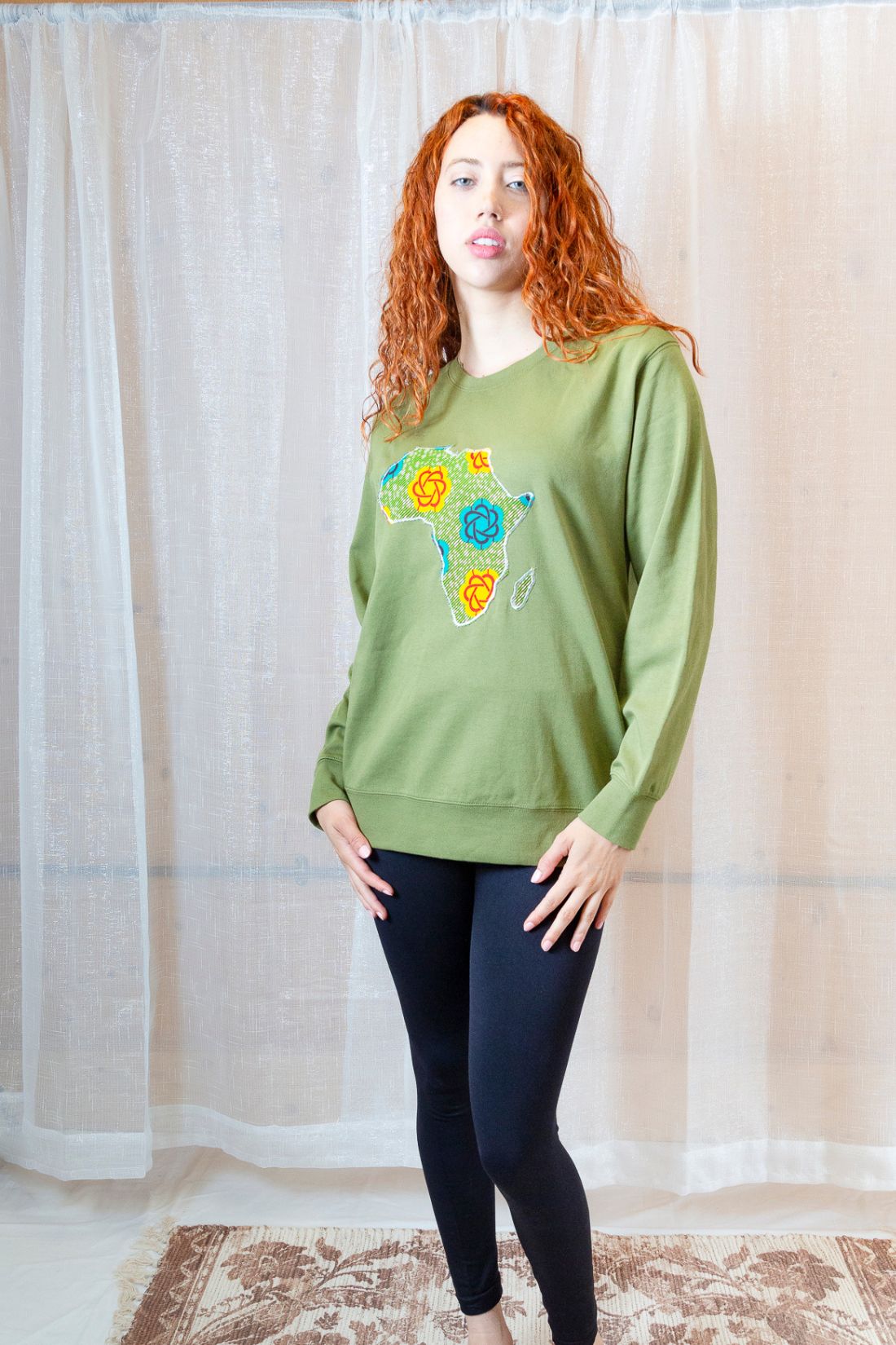 A person wearing a green sweatshirt with a map of Africa on it