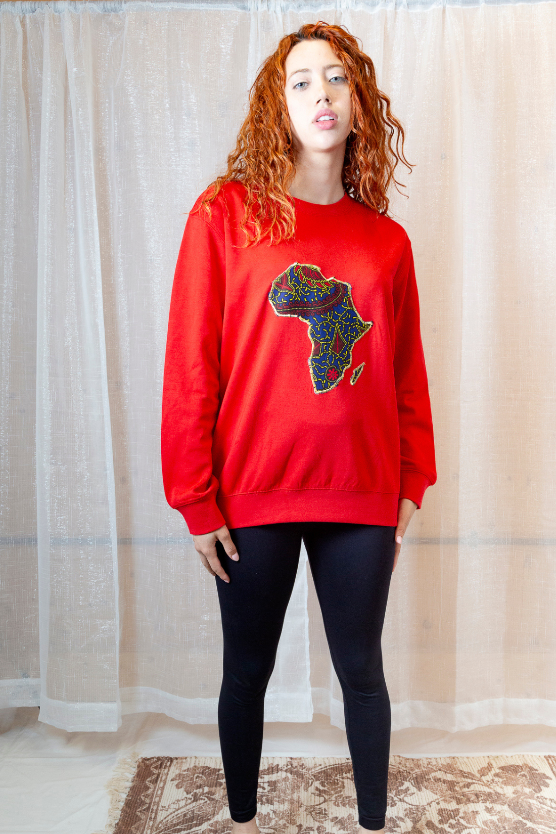 A person wearing a red sweatshirt with an Africa map on it