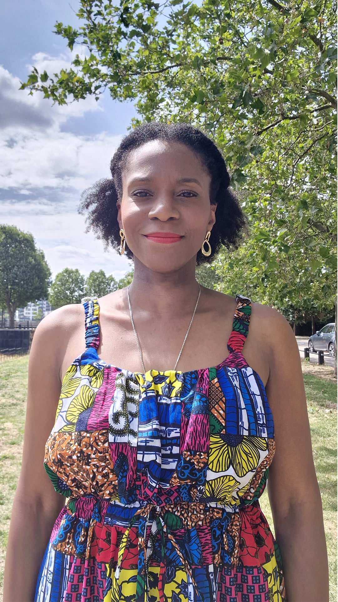 A close up of a woman, wearing the colourful maxi print dress, standing confidently.