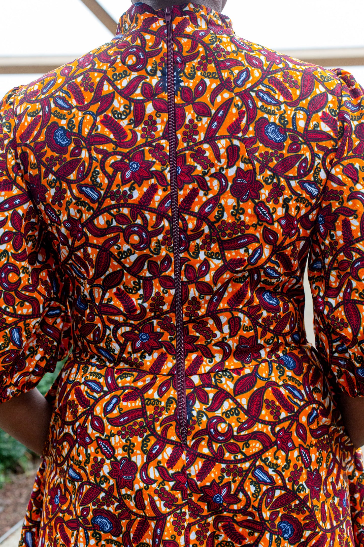 A rear view of the orange dress, showcasing the zipper closure at the back for added style and functionality.