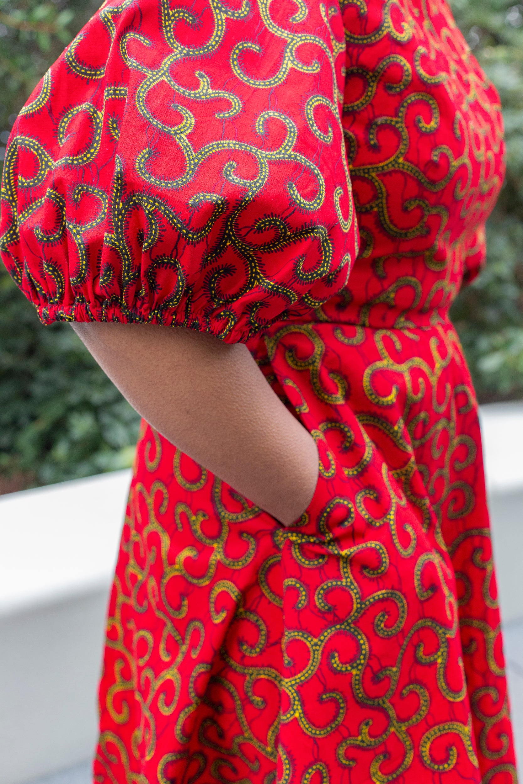 A close-up view highlighting the charming puff sleeve and a practical pocket of the red short dress.